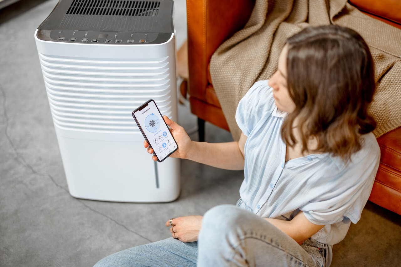 rsz woman sitting near air purifier and moisturizer ap 2023 11 27 05 16 09 utc